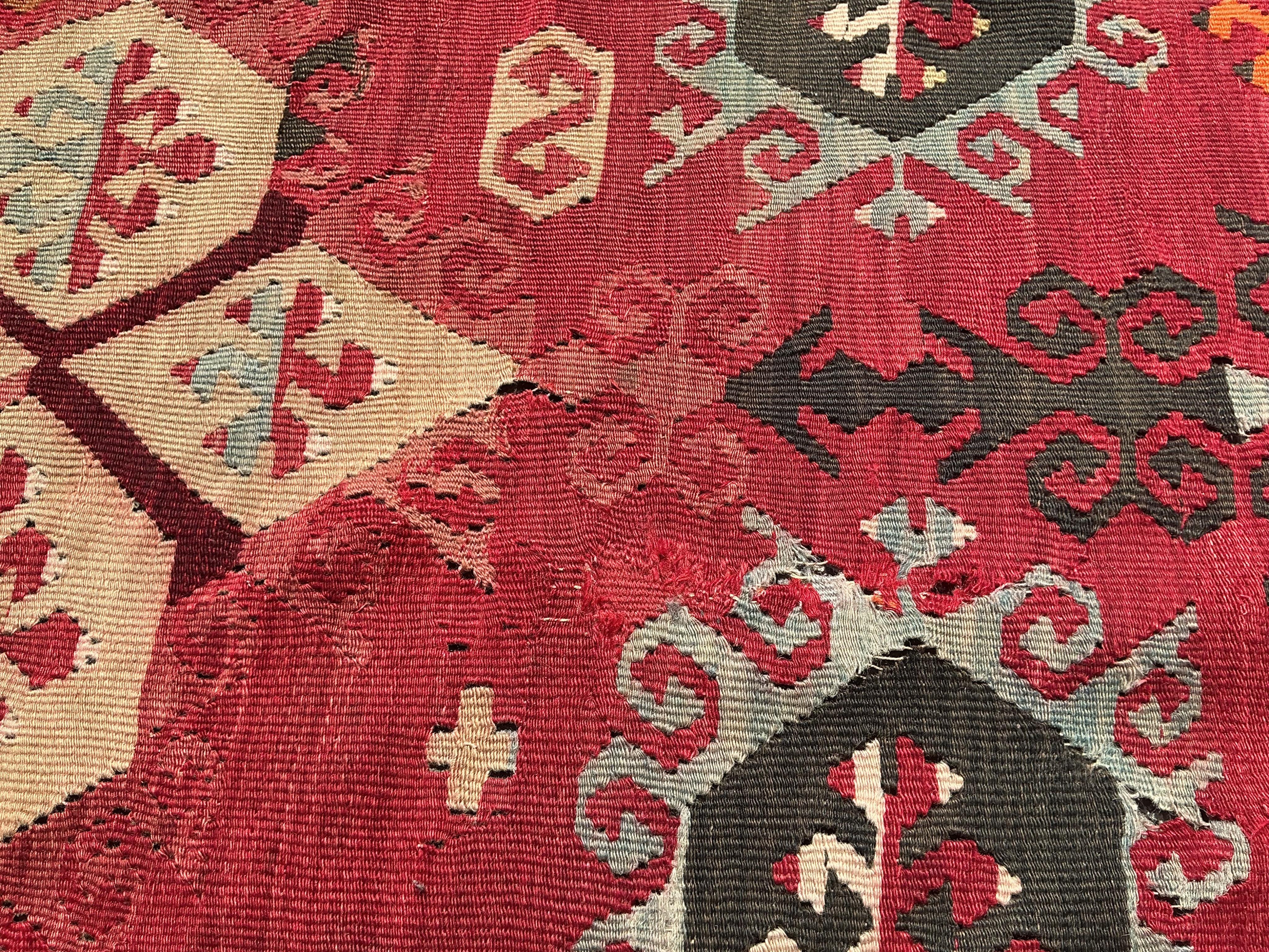 A Turkish Anatolian Kilim polychrome flatweave carpet, woven with geometric lozenges, on a pink field, 350 x 273cm